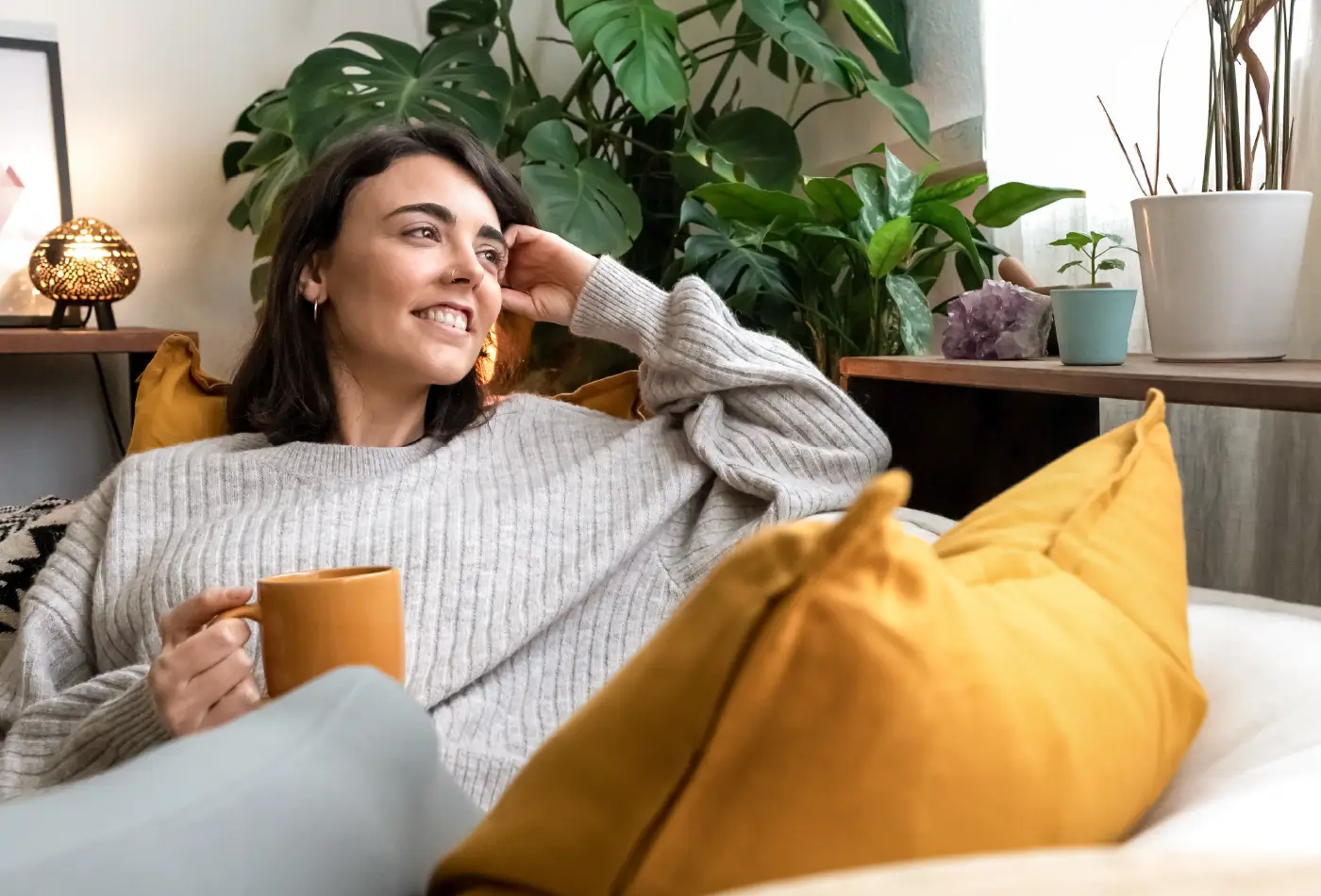 mujer en un sofá con una taza de te, feliz y en paz